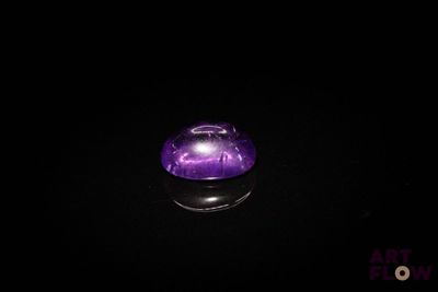 une image représentant une boule de cristal violette posée sur une surface noire