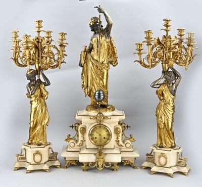 three gold colored statues and a clock on a table