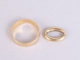 two gold rings on a white surface with a small ring in the middle