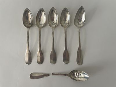 six cuillères et un repose-cuillère sur une surface blanche