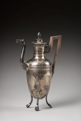 une théière ancienne en argent, munie d'une poignée en bois et posée sur un socle