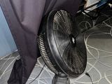 un ventilateur posé par terre devant un rideau