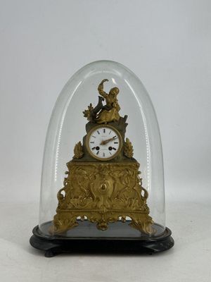 une horloge en or sous un dôme de verre sur une table