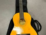 une guitare orange avec un étui noir posée par terre