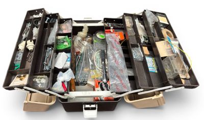 une valise remplie d'objets, posée sur une surface blanche