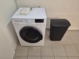 une machine à laver et une poubelle dans un coin de la pièce
