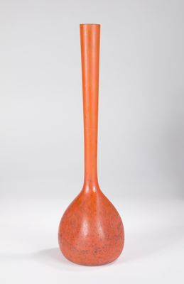 un vase orange posé sur une table blanche