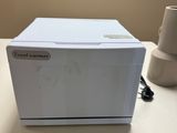 a white microwave sitting on a table next to a cup