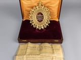 an image of a gold medal in a wooden box with a red velvet cover