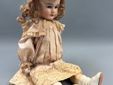 an antique doll sitting on the ground with her legs crossed