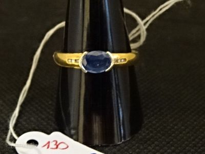 une bague en or sertie d'une pierre bleue, à côté d'une étiquette de prix