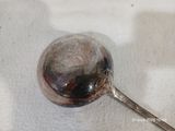 une cuillère en argent posée sur une nappe blanche, le manche vers le bas