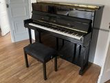 a piano in the corner of a room next to a chair