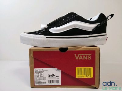 une boîte sur laquelle est posée une paire de chaussures noires et blanches