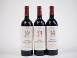three bottles of red wine sitting next to each other on a white surface