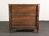 a small wooden chest of drawers on a carpeted floor