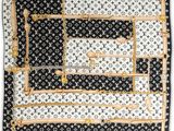 a black and white square scarf with a gold border