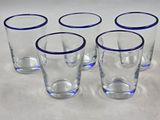 six verres aux bords bleus sont alignés sur une surface blanche