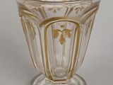 a glass cup that has a gold design on it