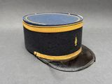 une image représentant un chapeau bleu orné d'une bordure dorée sur un fond gris