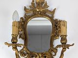 un miroir doré richement décoré, orné de deux bougies et d'un bougeoir