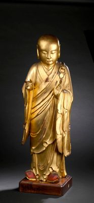 statue of a golden buddha on a wooden base with a black background