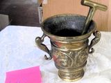 a metal cup with a hammer in it sitting on a table
