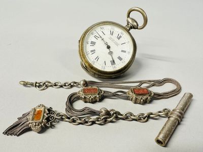 a silver pocket watch and a chain with a bird on it