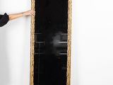 une femme debout près d'un grand miroir dans une pièce