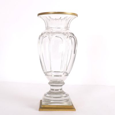 un vase en verre transparent à bord doré, posé sur un socle en bois