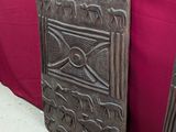 une paire de panneaux de porte anciens en bois sculpté posés sur une table recouverte d'une nappe rouge