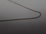 silver chain on a white surface with a single diamond on the end of the chain