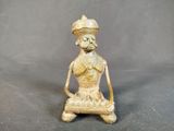 une vieille figurine en bronze représentant une femme assise sur un tabouret