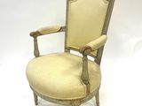 une vieille chaise avec une assise rembourrée beige et un cadre en bois