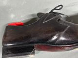 a black shoe with a red sole on a white surface
