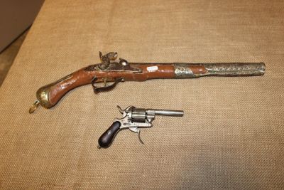 un vieux pistolet et un revolver sont posés sur une table
