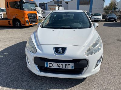 La voiture blanche est garée sur le parking, à côté d'un camion.