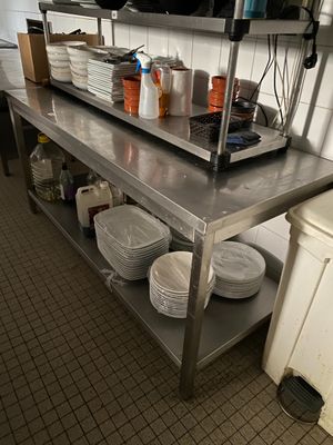 une grande table en acier inoxydable dans une cuisine, sur laquelle sont posés des plats
