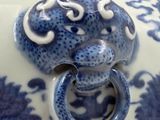 a close up of a blue and white vase with a lion head