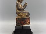 a statue of a person sitting on top of a wooden block
