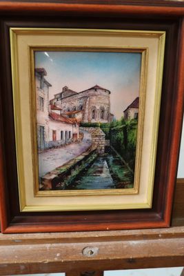 une peinture à l'huile représentant une scène de rue, dans un cadre en bois, posée sur une étagère