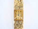 an image of a gold wrist watch with roman numerals on the face