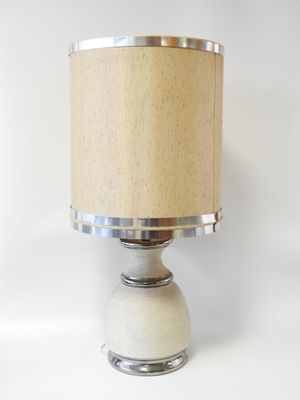 lampe de table beige et argentée avec un abat-jour beige sur fond blanc