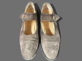 pair of gray sued shoes with buckles on a gray surface