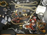 beaucoup de bijoux posés sur une table sur laquelle se trouve un chapeau