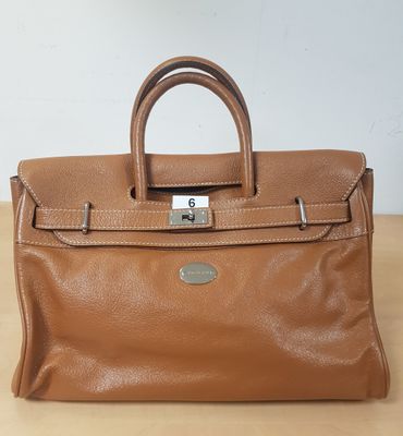 un sac à main en cuir marron posé sur une table en bois