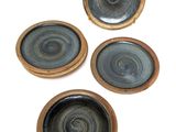 four plates with a circular design are sitting on a white surface