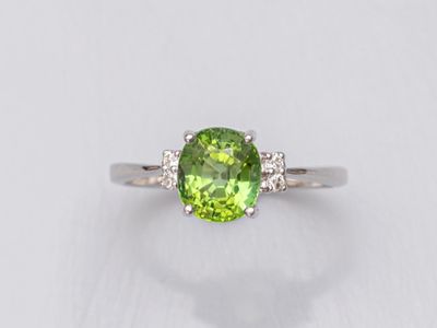 une bague en tourmaline verte et diamants sur fond blanc