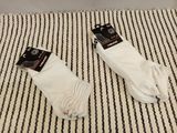 two pairs of white socks sitting on top of a black and white striped blanket