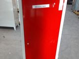 a red and white refrigerator in a warehouse with a sign on the door